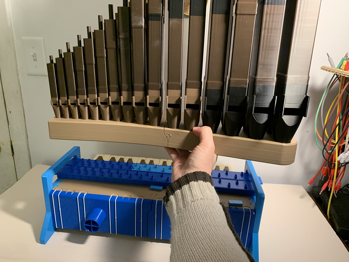 A hand lifting a row of pipes off the organ
