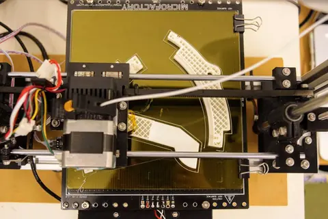 A small 3D printer printing a curved rim segment