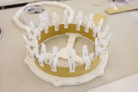 The paper shell held in place around the frame with many clothes pegs while the glue dries