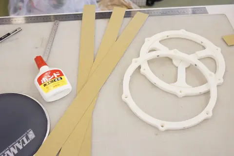 Strips of thick paper, a bottle of glue and the assembled rim and frame
