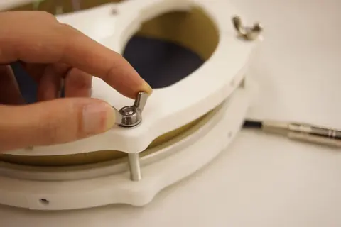 A hand turning a bolt on the pad's rim