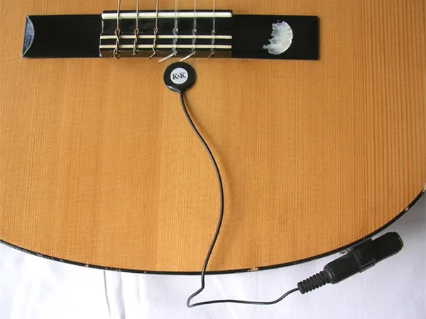 A disc piezo pickup stuck to an acoustic guitar top